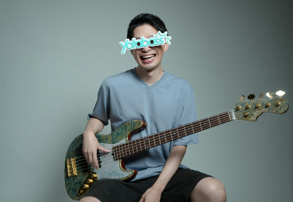 yotabassがベースを持って笑っている