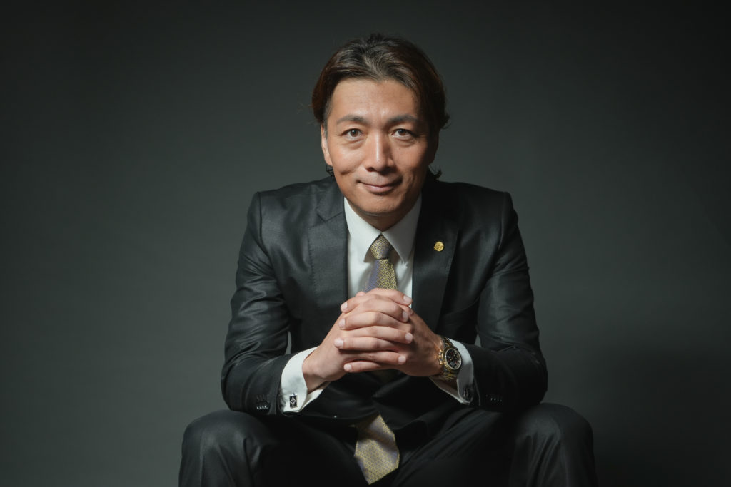 男性が椅子に座り手を組んでいる