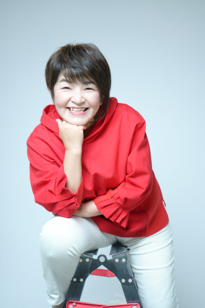 脚立にまたがった赤いパーカーを着た女性