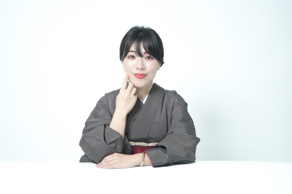 着物を着た女性が白のテーブルに肘をかけ微笑んでいる