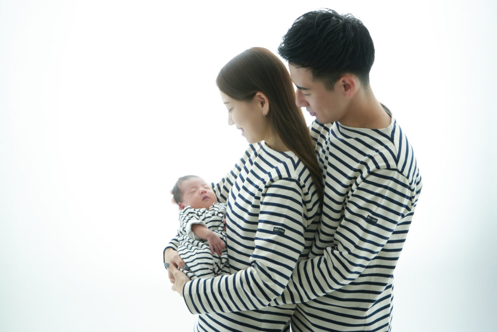 パパとママが新しく生まれてきた子供を抱いている写真