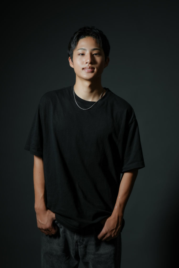 黒いTシャツを着た男性が立っている写真