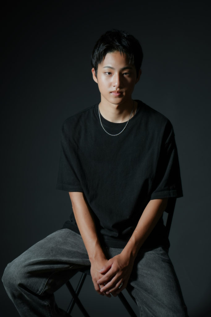 黒いTシャツを着た男性が椅子に座っている写真