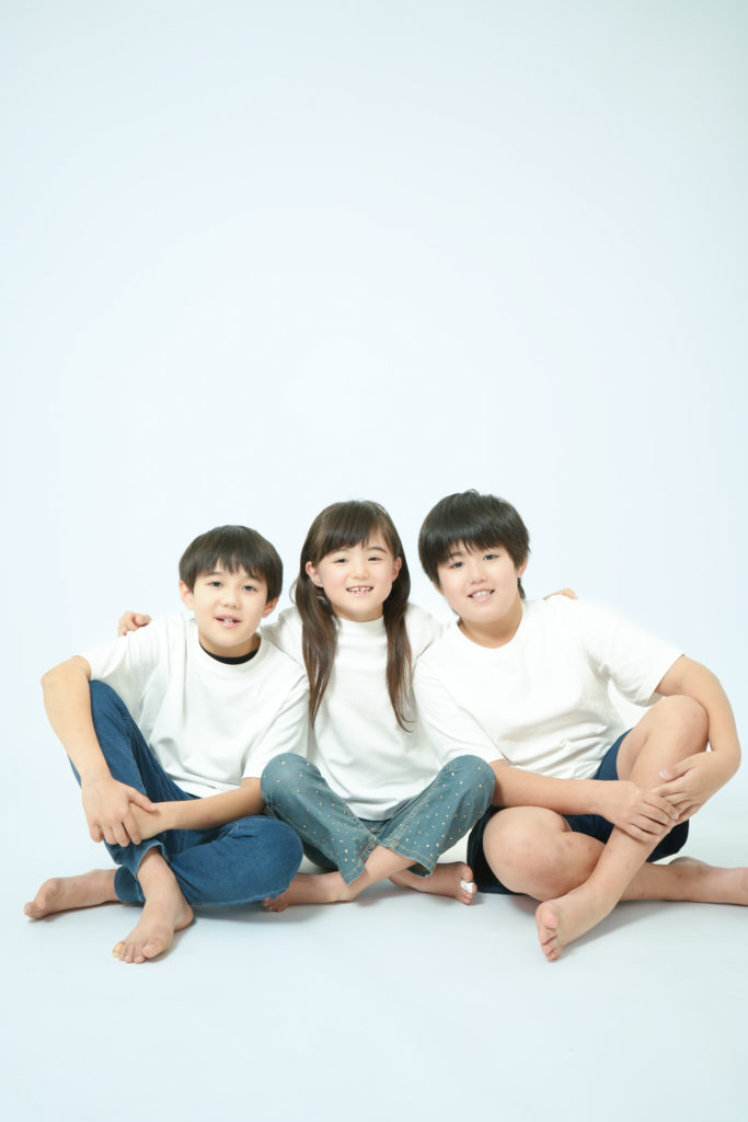 白Tシャツとデニムでリンクコーデした3兄妹の写真