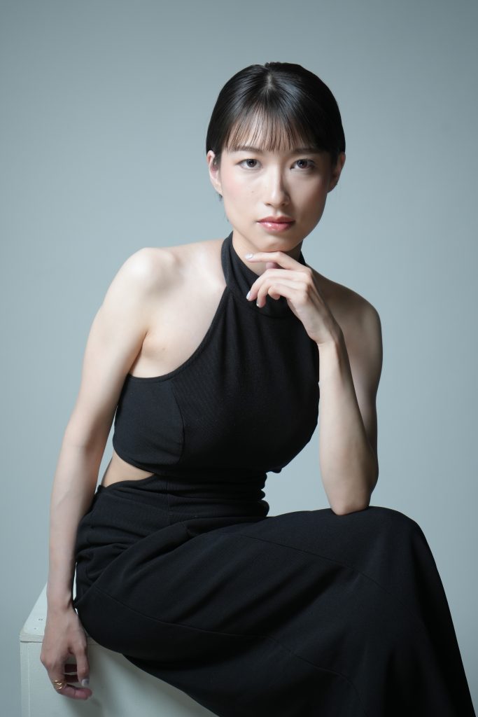 黒のドレスを着た女性が顎に手を掛けてポーズをとっている写真