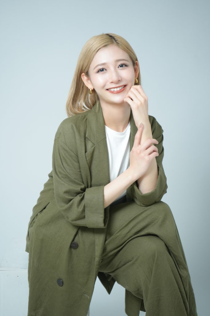 グリーンのセットアップを着て笑顔でポーズをとる女性の写真