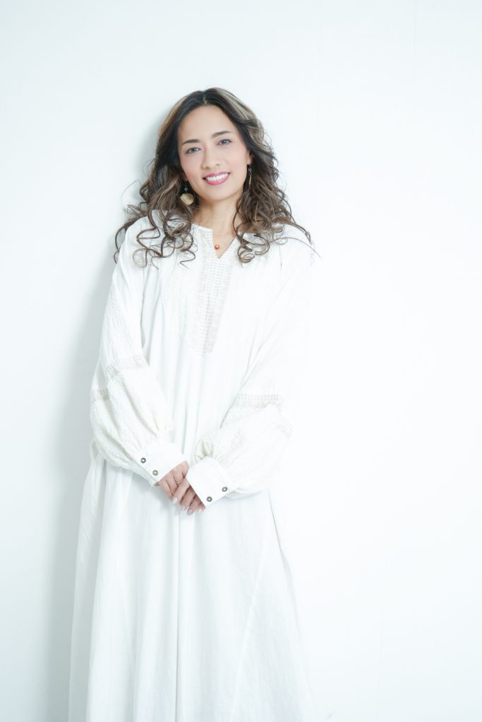 白のワンピースを着た女性が立っている写真