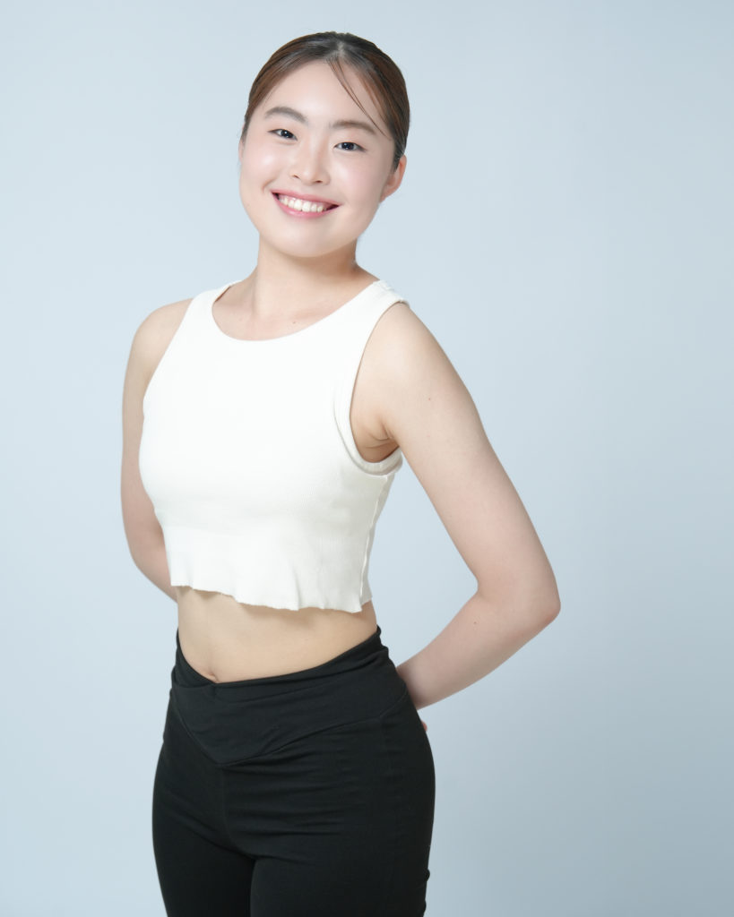 若い女性が手を後ろに組んで笑っている