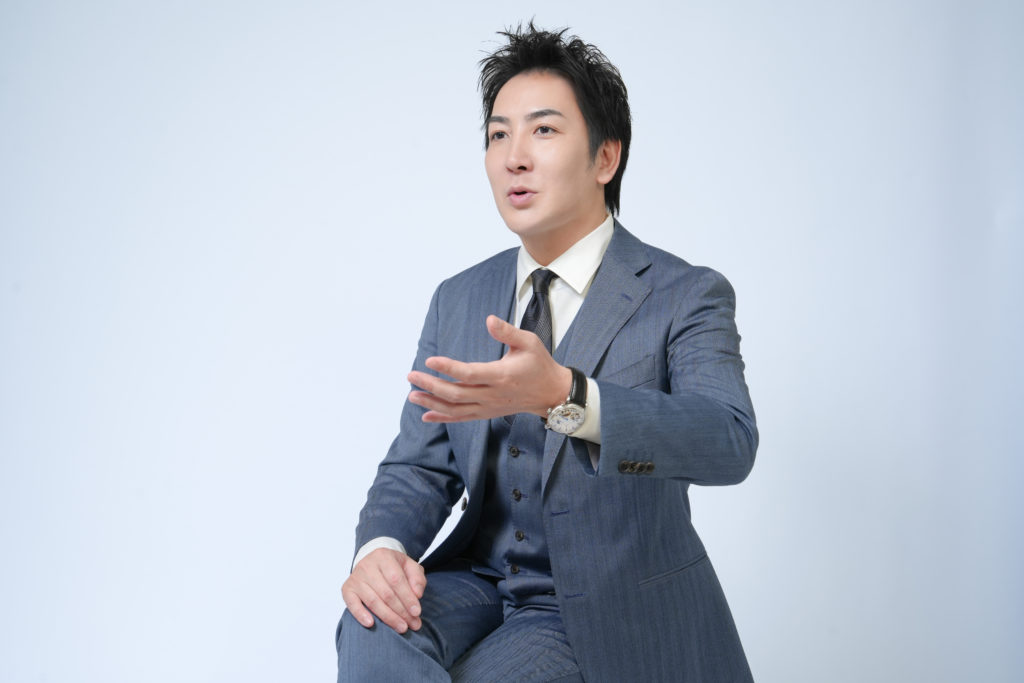 Studio Fictionで撮影した、白色背景でスーツを着た男性がプレゼンしているポートレート写真