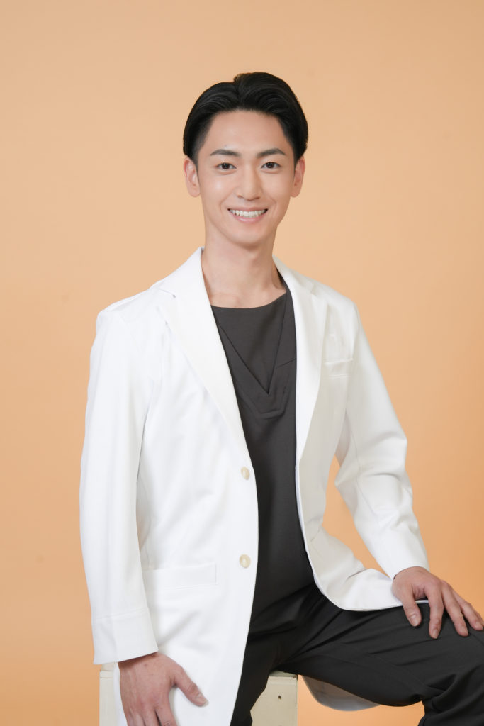 Studio Fictionで撮影した、　ベージュ背景で立つ男性ドクターのポートレート写真